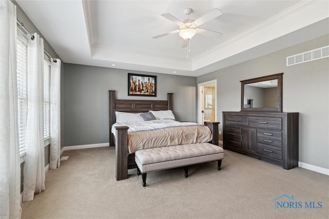 bedroom with a raised ceiling, baseboards, visible vents, and light carpet