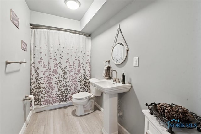 full bath with baseboards, a shower with curtain, wood finished floors, and toilet