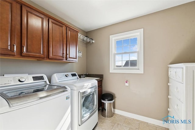 laundry area featuring a sink, baseboards, cabinet space, and washer and clothes dryer