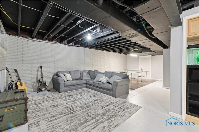 living room with finished concrete floors, brick wall, and baseboards