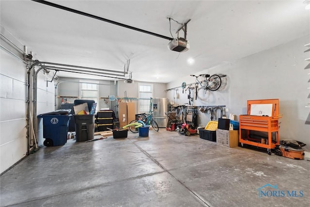 garage with a garage door opener and stainless steel fridge with ice dispenser