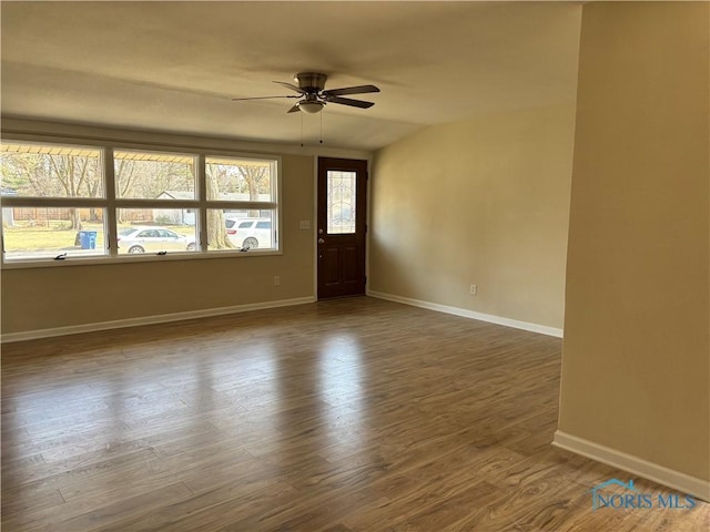 empty room featuring baseboards, dark wood-style flooring, and ceiling fan