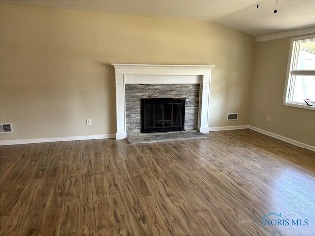 unfurnished living room with visible vents, lofted ceiling, a stone fireplace, and dark wood-style flooring