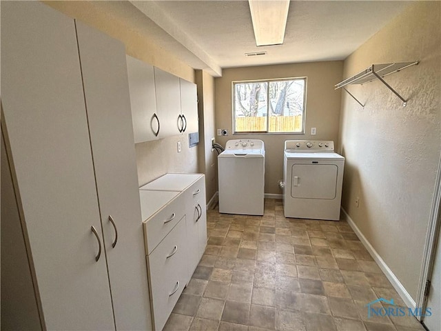 washroom with visible vents, stone finish floor, washer and dryer, cabinet space, and baseboards