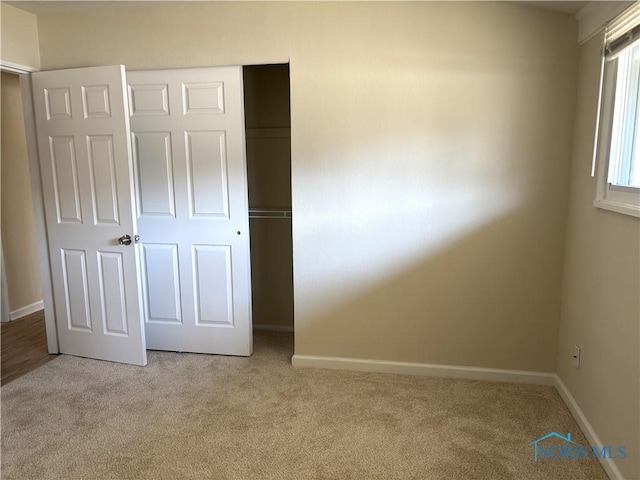 unfurnished bedroom with light carpet, baseboards, and a closet