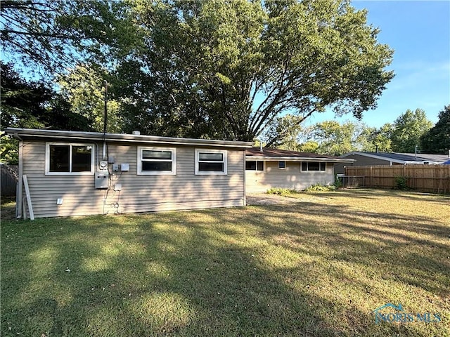 rear view of house with a lawn and fence