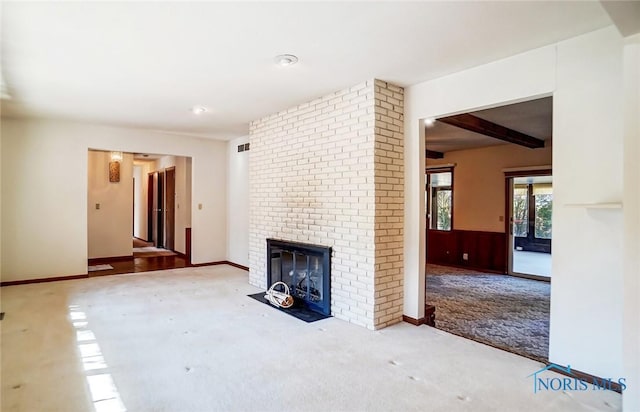 unfurnished living room featuring visible vents, a wainscoted wall, carpet floors, beam ceiling, and a fireplace