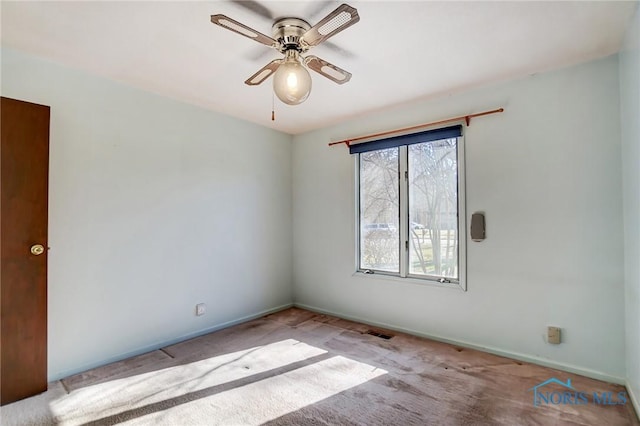 carpeted spare room with visible vents, baseboards, and a ceiling fan