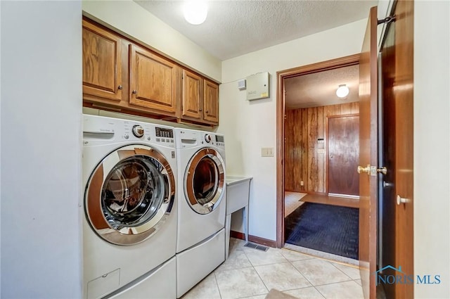 laundry area featuring visible vents, washer and clothes dryer, light tile patterned floors, cabinet space, and a textured ceiling