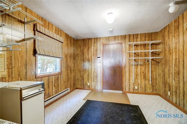 interior space featuring a baseboard radiator, wooden walls, and a textured ceiling