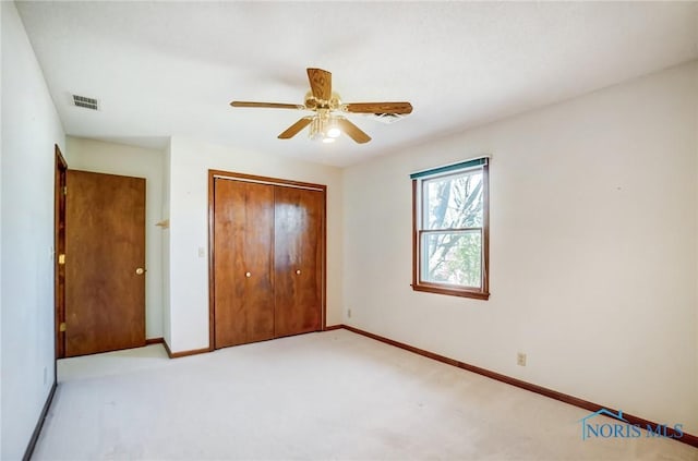 unfurnished bedroom featuring visible vents, baseboards, light colored carpet, and a closet