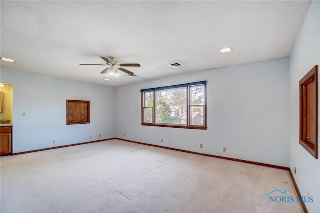 spare room with visible vents, light carpet, baseboards, and a ceiling fan