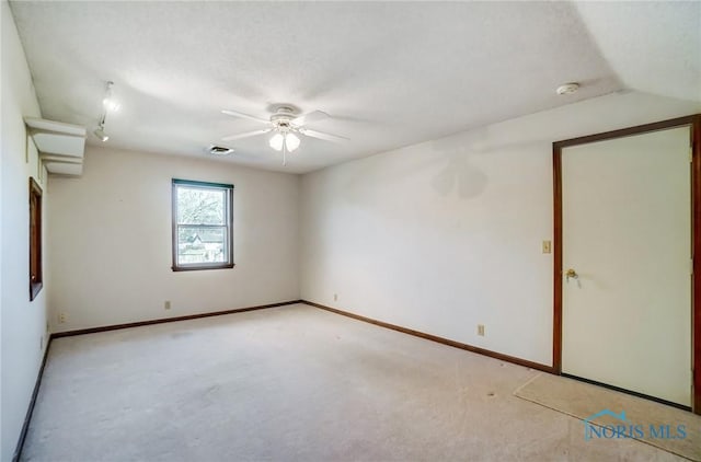 spare room with carpet flooring, visible vents, baseboards, and a ceiling fan