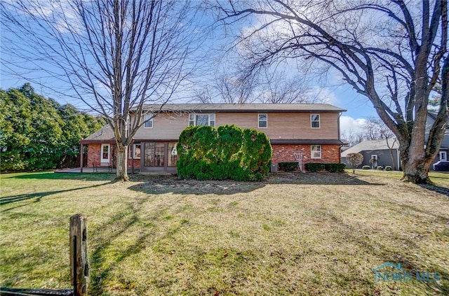 back of house with a yard and brick siding