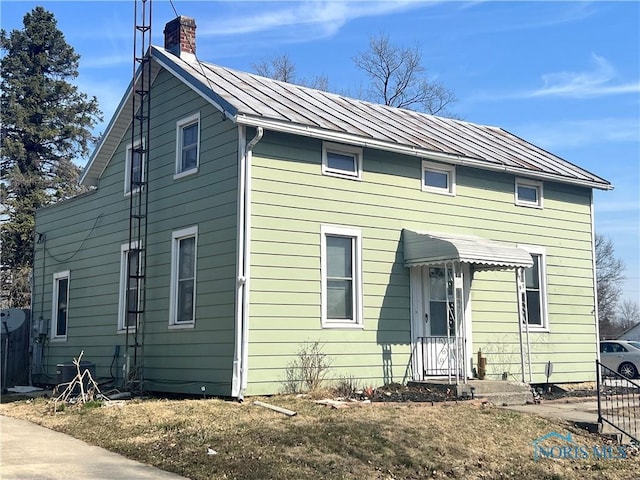 view of front of property with metal roof, a chimney, and a standing seam roof