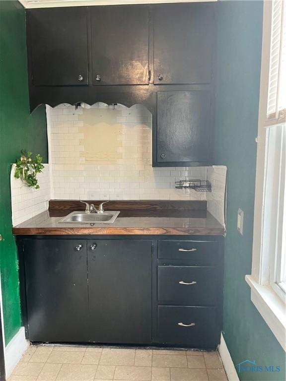 kitchen featuring a sink, decorative backsplash, and light tile patterned floors