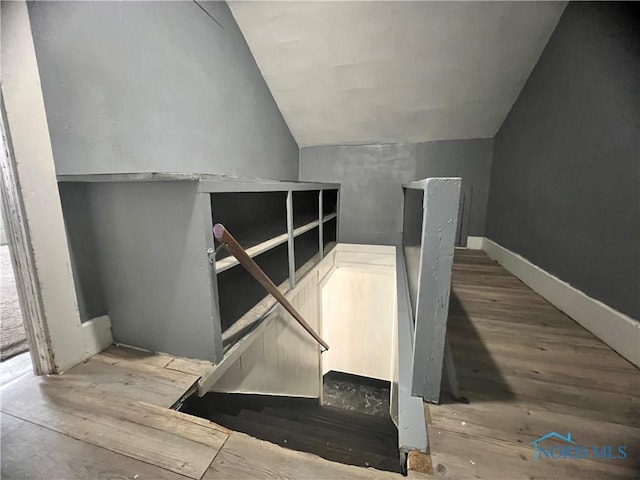 staircase featuring wood finished floors and vaulted ceiling