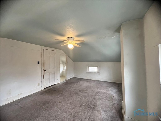 bonus room with vaulted ceiling, a ceiling fan, baseboards, and dark carpet