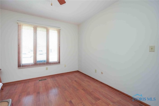 unfurnished room featuring ceiling fan, wood finished floors, visible vents, and baseboards