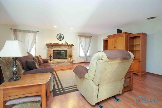 living room with a fireplace, visible vents, light wood finished floors, and baseboards