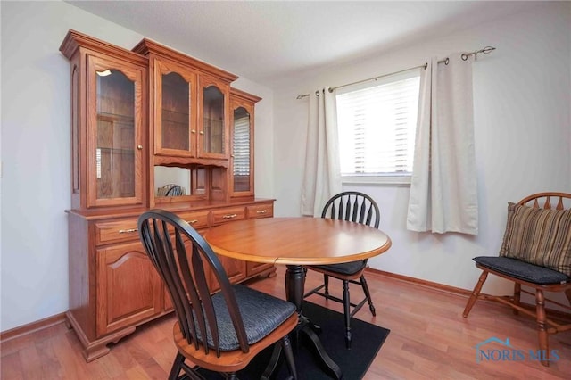 dining space featuring baseboards and light wood-style floors