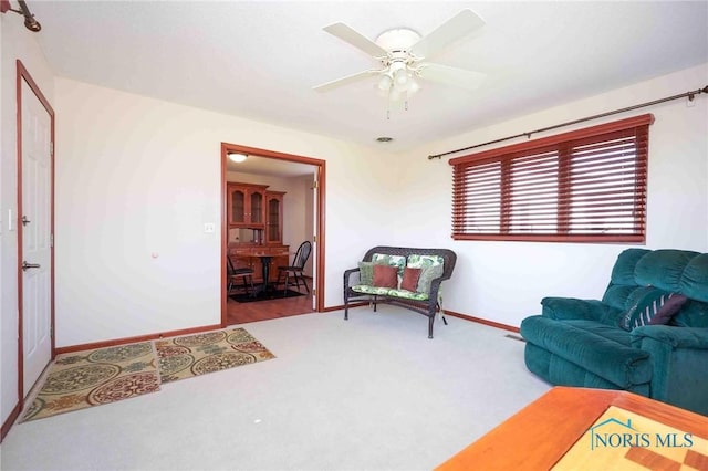 living area with baseboards, carpet, and a ceiling fan