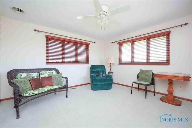 living area featuring visible vents, carpet floors, a healthy amount of sunlight, and ceiling fan