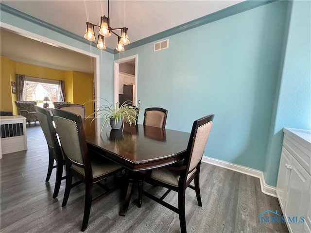 dining room with an inviting chandelier, baseboards, visible vents, and dark wood-style flooring