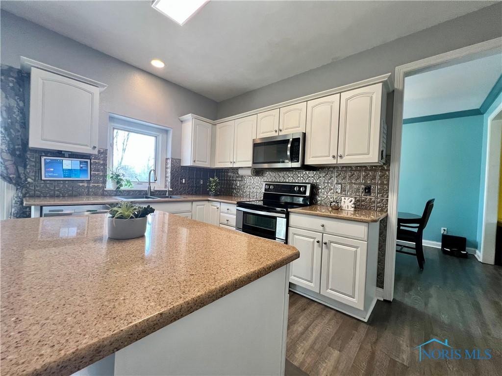 kitchen with a sink, decorative backsplash, appliances with stainless steel finishes, and white cabinetry