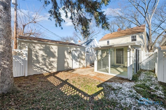 rear view of house featuring a chimney, fence, and a sunroom