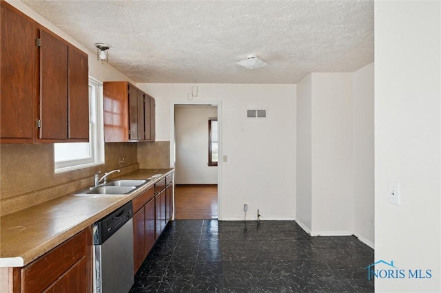 kitchen with visible vents, a sink, stainless steel dishwasher, backsplash, and baseboards