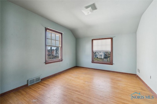 additional living space featuring vaulted ceiling, visible vents, baseboards, and wood-type flooring