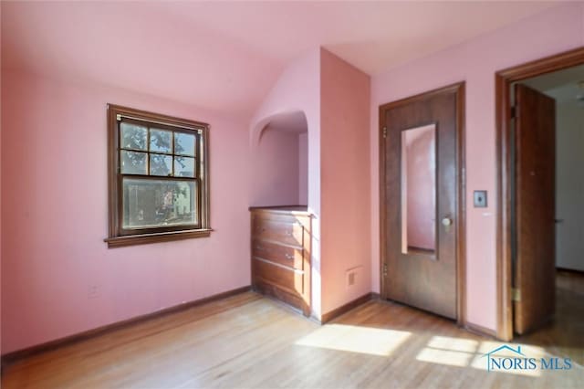 unfurnished bedroom featuring elevator, baseboards, and light wood finished floors