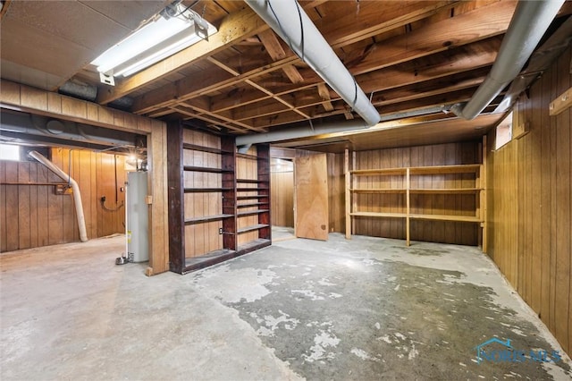 unfinished basement featuring gas water heater and wood walls