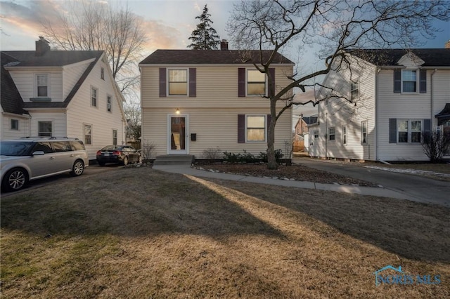 view of front of house featuring a lawn, a chimney, and entry steps