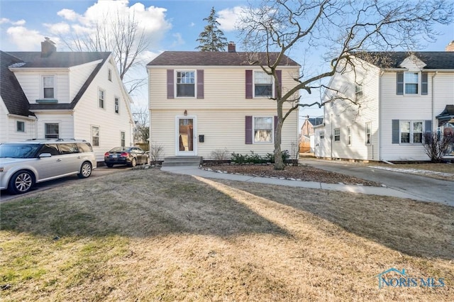 view of front of property with a front yard, a chimney, and entry steps