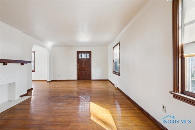 foyer with visible vents, arched walkways, baseboards, and wood finished floors