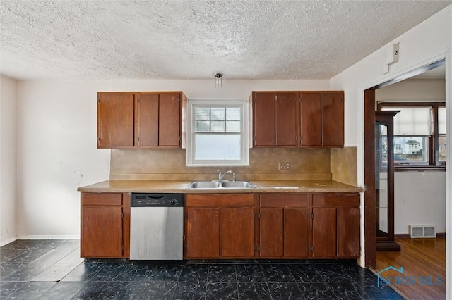 kitchen with visible vents, light countertops, stainless steel dishwasher, brown cabinetry, and a sink