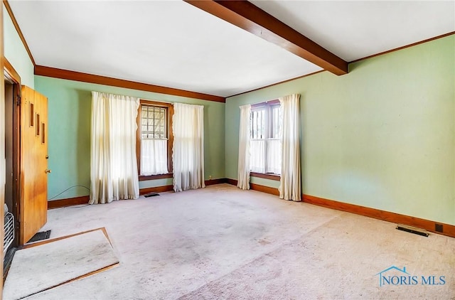 carpeted spare room with beamed ceiling, baseboards, visible vents, and ornamental molding