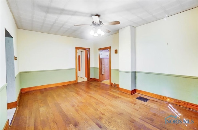 spare room featuring visible vents, baseboards, wood finished floors, and a ceiling fan