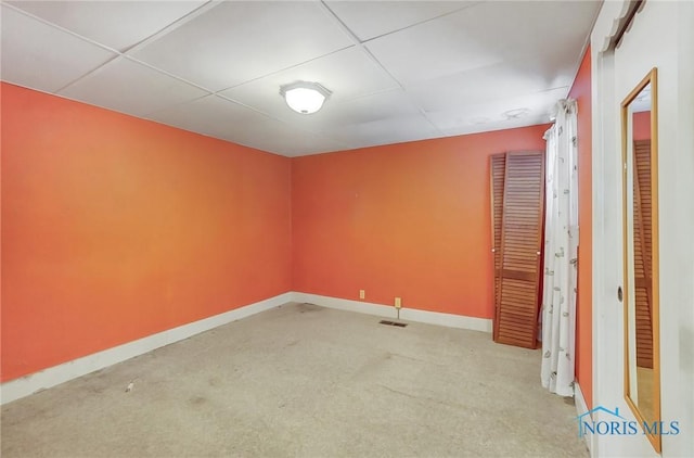 unfurnished room with light carpet, a drop ceiling, visible vents, and baseboards