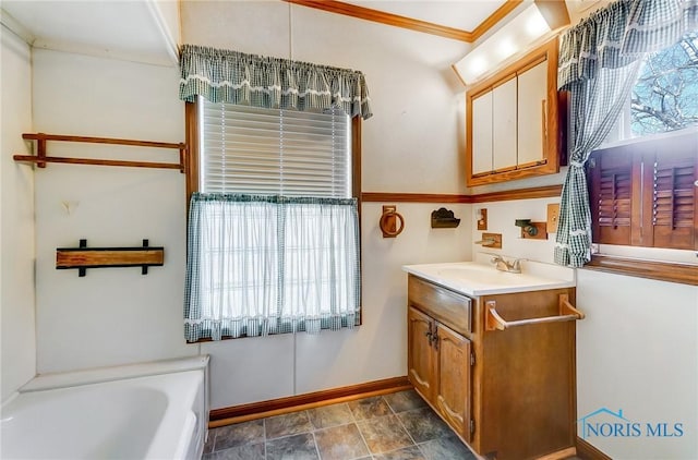 full bath with baseboards, vanity, a garden tub, and ornamental molding