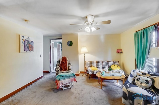 carpeted living area with baseboards and a ceiling fan