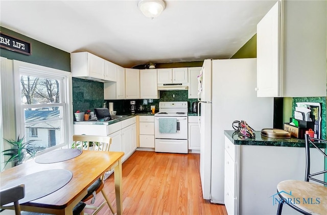 kitchen featuring white appliances, under cabinet range hood, white cabinetry, dark countertops, and backsplash