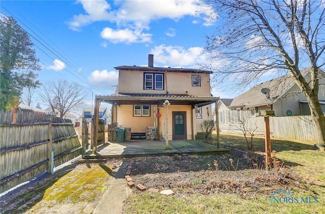 rear view of property featuring a fenced backyard and a chimney