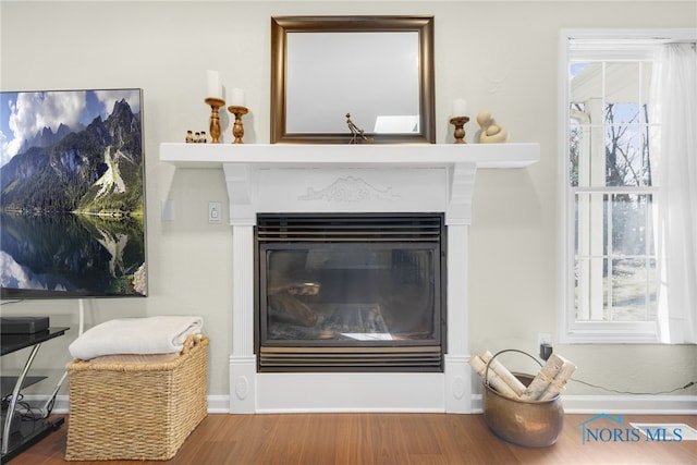 interior details with a glass covered fireplace, baseboards, and wood finished floors