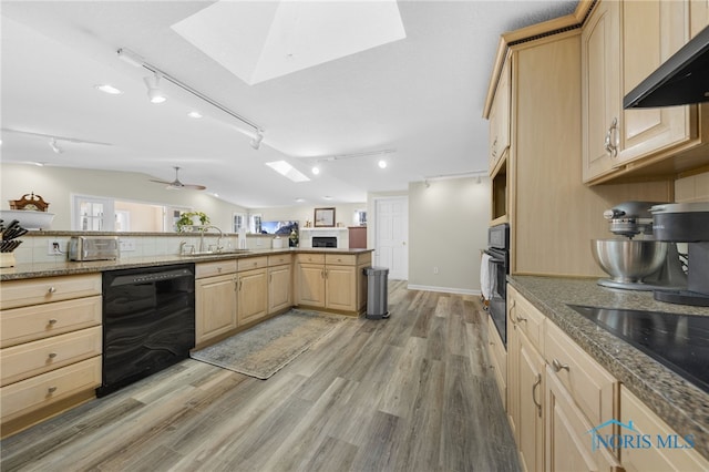 kitchen featuring light brown cabinets, a sink, black appliances, extractor fan, and lofted ceiling with skylight