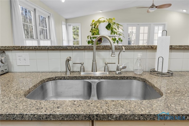 interior details with decorative backsplash, stone countertops, a ceiling fan, and a sink