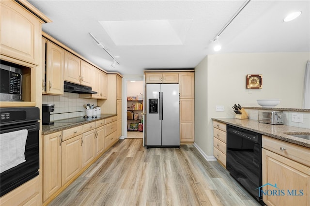 kitchen with under cabinet range hood, tasteful backsplash, black appliances, and light brown cabinetry