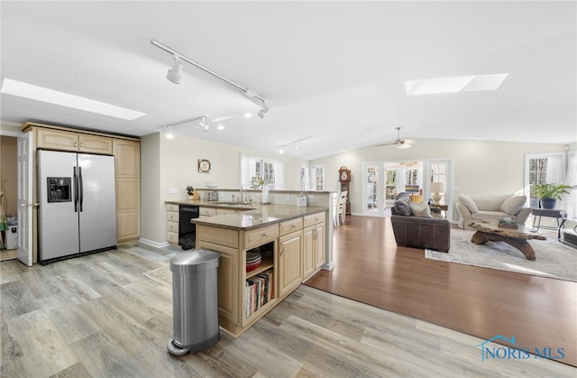 kitchen featuring light brown cabinetry, stainless steel fridge, lofted ceiling with skylight, and a sink